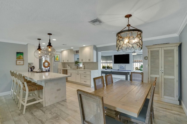 dining room with crown molding, visible vents, baseboards, light wood-type flooring, and an inviting chandelier