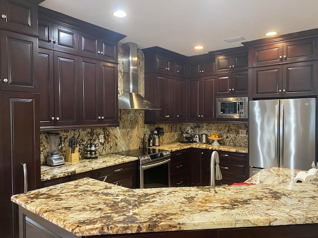 kitchen featuring appliances with stainless steel finishes, tasteful backsplash, light stone counters, and wall chimney exhaust hood