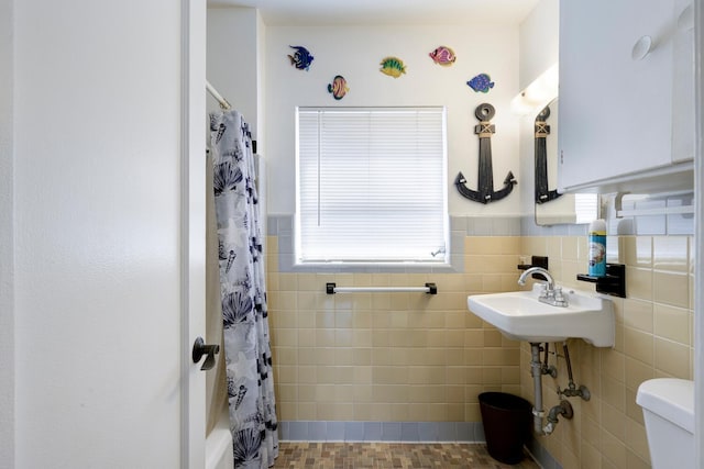 full bathroom featuring sink, shower / bath combo, toilet, and tile walls