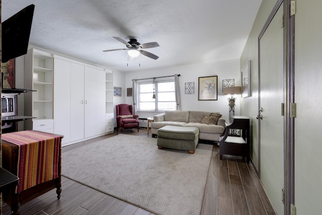 living room with dark hardwood / wood-style floors, ceiling fan, and a textured ceiling