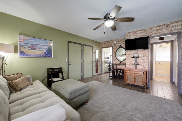 living room featuring dark hardwood / wood-style floors, ceiling fan, a healthy amount of sunlight, and brick wall