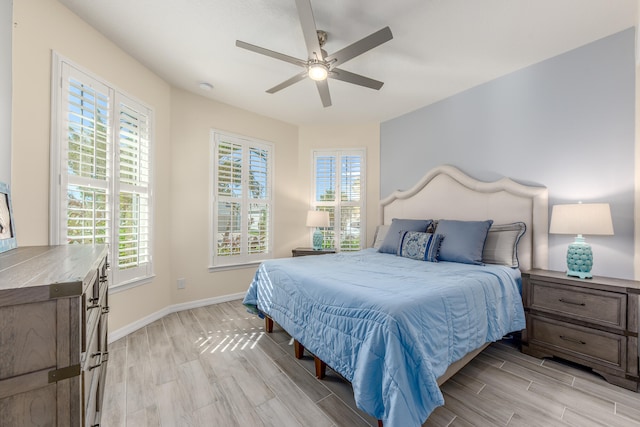 bedroom with ceiling fan, light hardwood / wood-style flooring, and multiple windows