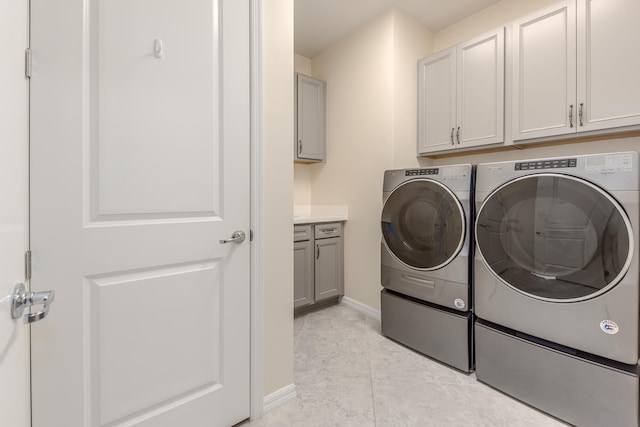 clothes washing area with cabinets, light tile patterned floors, and separate washer and dryer