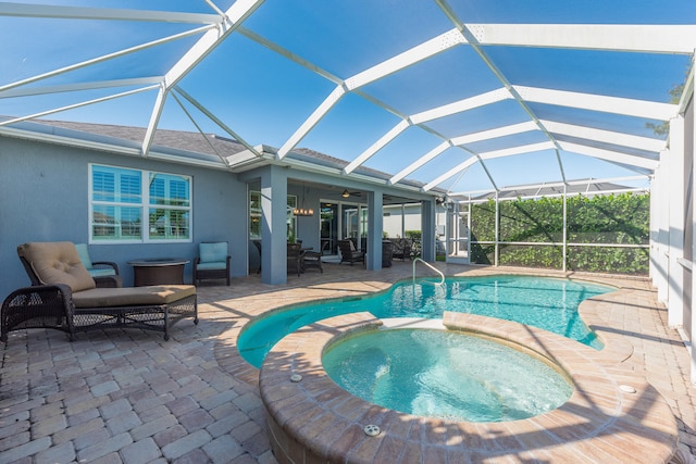 view of pool with glass enclosure, ceiling fan, an in ground hot tub, and a patio