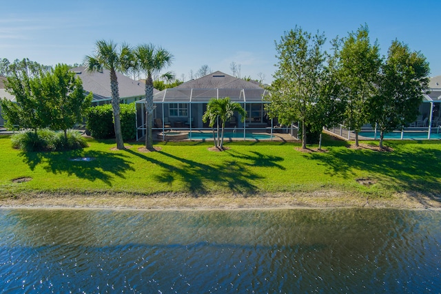 back of property with a lawn, glass enclosure, and a water view