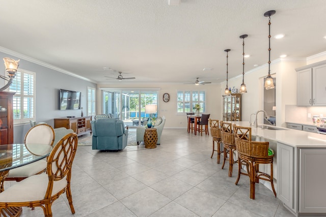 dining area with ceiling fan, sink, light tile patterned floors, and ornamental molding