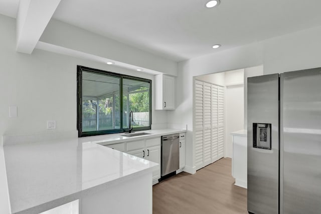 kitchen with sink, white cabinetry, light wood-type flooring, kitchen peninsula, and stainless steel appliances