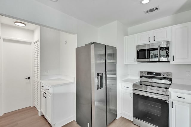 kitchen featuring appliances with stainless steel finishes, white cabinets, and light hardwood / wood-style floors