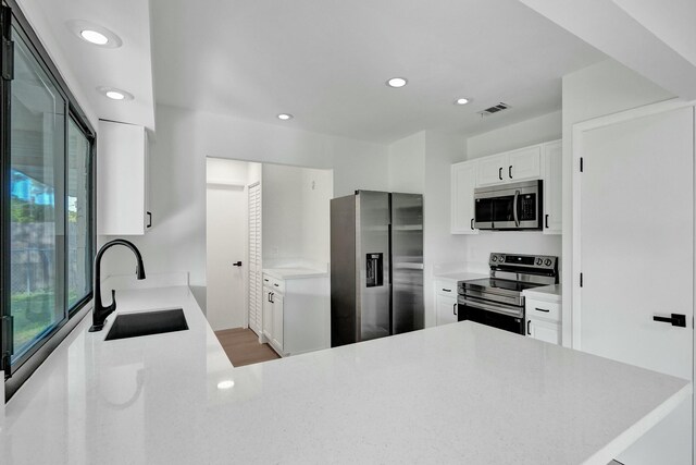 kitchen with stainless steel appliances, white cabinetry, and light hardwood / wood-style floors