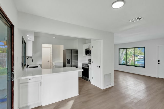 kitchen featuring sink, stainless steel appliances, kitchen peninsula, and white cabinets