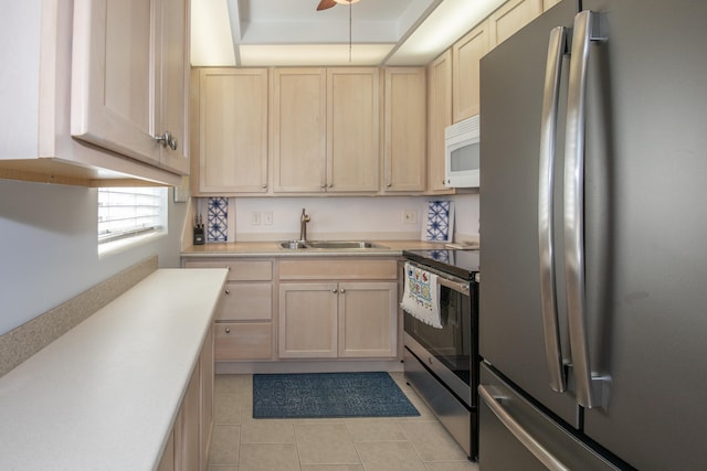 kitchen featuring appliances with stainless steel finishes, light tile patterned floors, light brown cabinetry, and sink