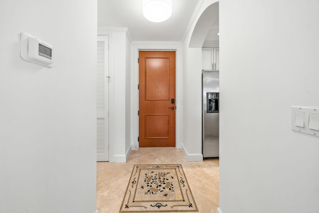 corridor featuring light tile patterned flooring, a textured ceiling, and ornamental molding