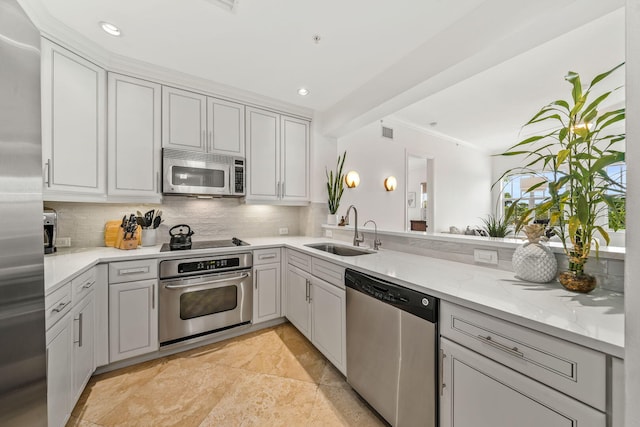 kitchen with sink, light stone counters, decorative backsplash, appliances with stainless steel finishes, and ornamental molding