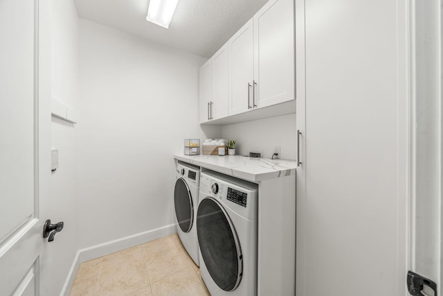 laundry room with washer and clothes dryer, cabinets, light tile patterned floors, and a textured ceiling