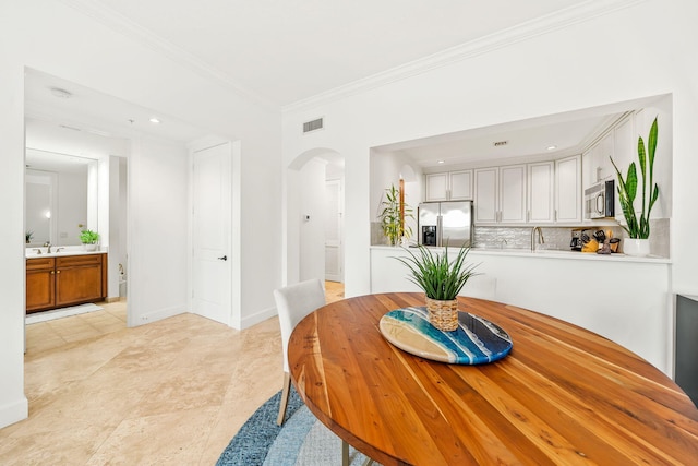 tiled dining space featuring ornamental molding and sink