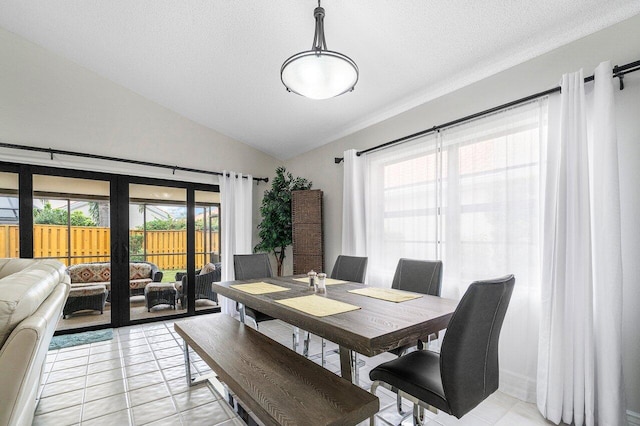 dining area featuring lofted ceiling, light tile patterned floors, and a textured ceiling