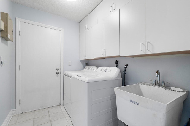 washroom featuring sink, light tile patterned floors, washer and clothes dryer, cabinets, and a textured ceiling