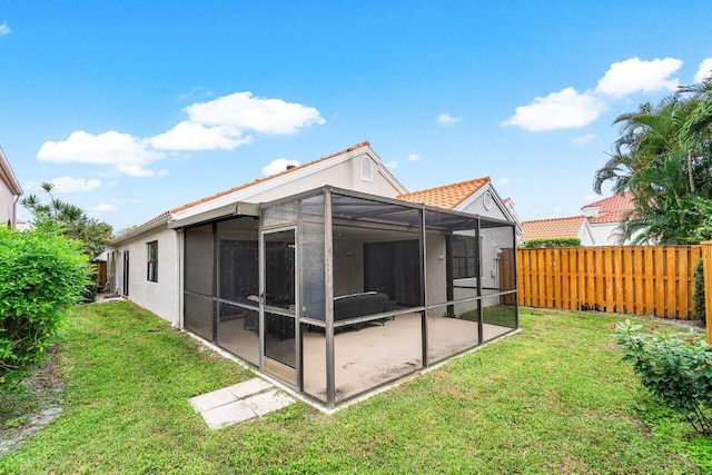 rear view of property featuring a yard and a sunroom