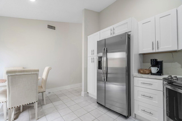 kitchen with stainless steel appliances, light tile patterned floors, and white cabinets