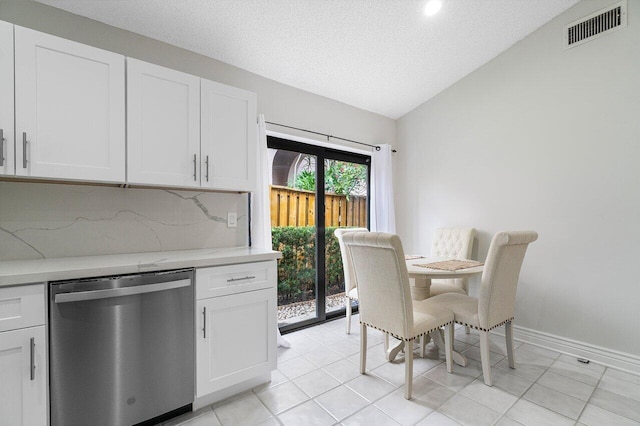 kitchen with tasteful backsplash, dishwasher, vaulted ceiling, and white cabinets