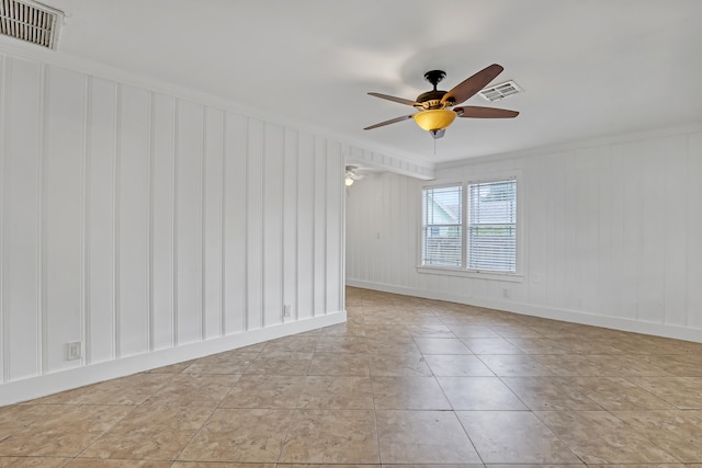 empty room with ceiling fan, light tile patterned flooring, and ornamental molding