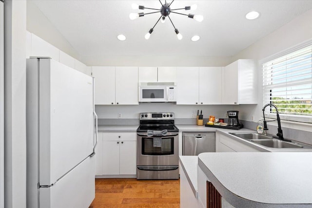 kitchen with white cabinetry, sink, a notable chandelier, light hardwood / wood-style floors, and appliances with stainless steel finishes