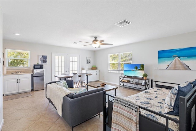 living room with french doors, a textured ceiling, ceiling fan, sink, and light tile patterned floors