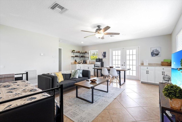 living room with plenty of natural light, light tile patterned flooring, a textured ceiling, and french doors