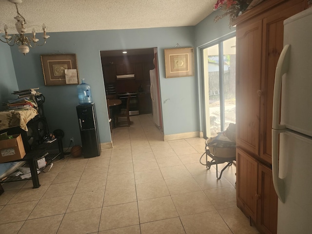 hallway with light tile patterned floors, a textured ceiling, and a notable chandelier