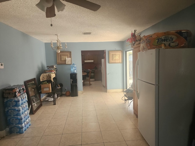 kitchen with ceiling fan with notable chandelier, white fridge, light tile patterned flooring, and a textured ceiling