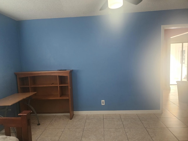 tiled empty room featuring ceiling fan and a textured ceiling