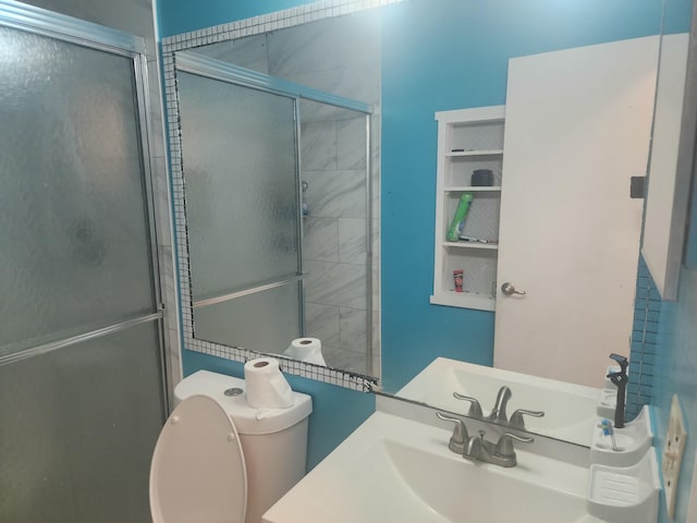 bathroom with toilet, a shower with shower door, and sink