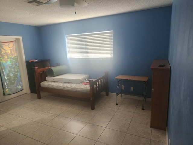 bedroom featuring ceiling fan, light tile patterned flooring, and a textured ceiling