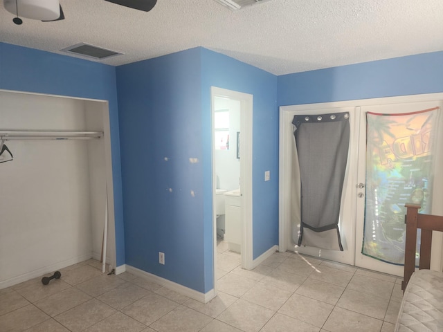 unfurnished bedroom featuring light tile patterned floors, a textured ceiling, a closet, and ceiling fan