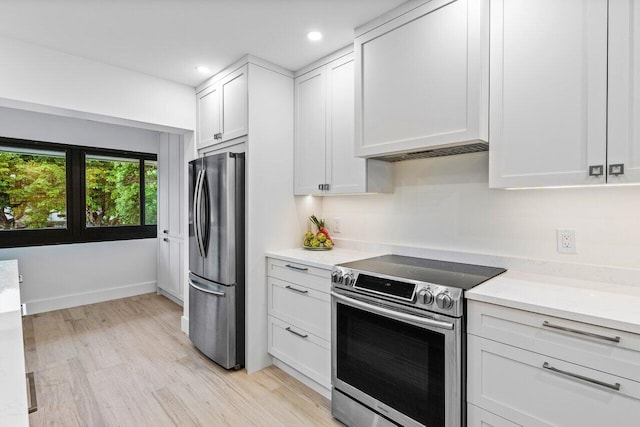 kitchen with light stone counters, light wood-type flooring, white cabinetry, and stainless steel appliances