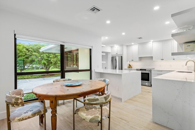 dining space with light hardwood / wood-style flooring and sink