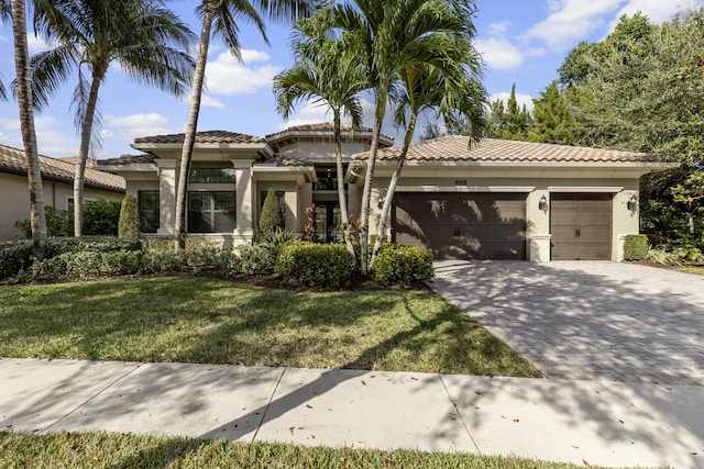 mediterranean / spanish house featuring a garage and a front lawn