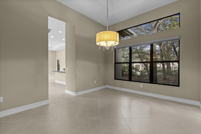 empty room featuring a notable chandelier and light tile patterned flooring