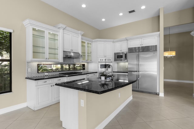 kitchen featuring white cabinetry, sink, built in appliances, light tile patterned floors, and a center island with sink