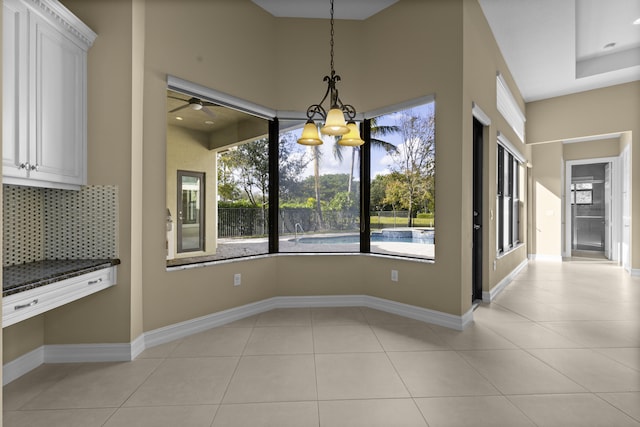 unfurnished dining area featuring light tile patterned floors and a chandelier