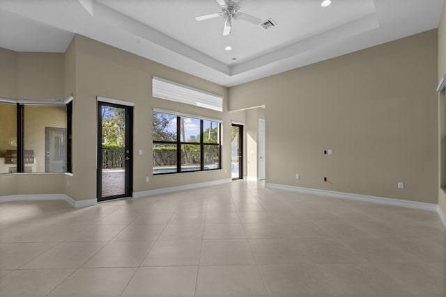 tiled empty room featuring a tray ceiling and ceiling fan