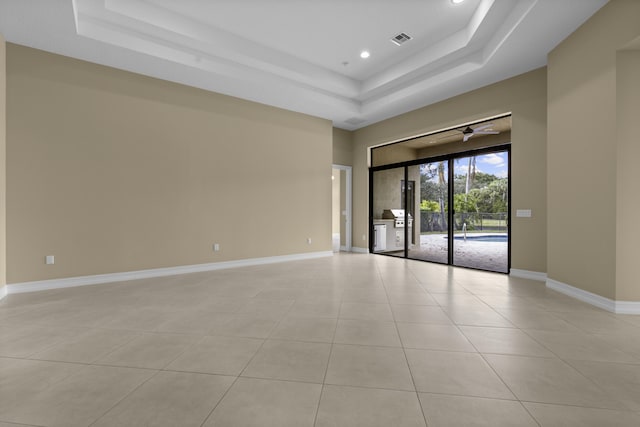 empty room with a tray ceiling and light tile patterned floors