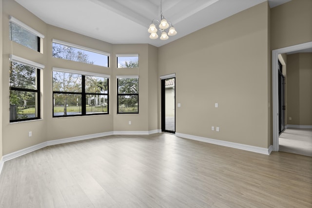 unfurnished room featuring an inviting chandelier and light hardwood / wood-style floors