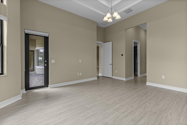 spare room with an inviting chandelier and light hardwood / wood-style floors