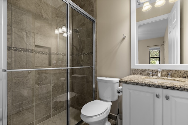 bathroom with vanity, a shower with door, and toilet