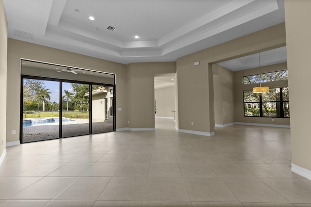 unfurnished room with light tile patterned floors and a tray ceiling