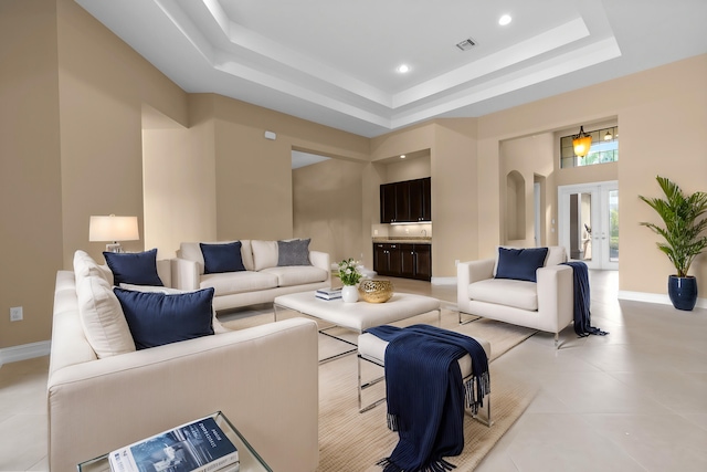 living room with a tray ceiling, french doors, and a towering ceiling