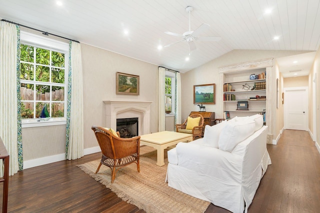 living room featuring built in shelves, ceiling fan, dark wood-type flooring, and lofted ceiling