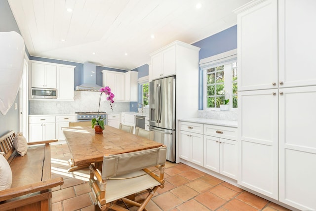 kitchen with white cabinetry, decorative backsplash, wall chimney exhaust hood, and stainless steel appliances