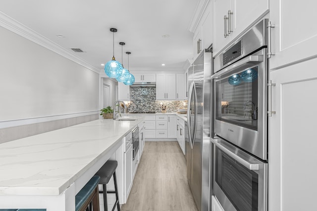 kitchen featuring sink, hanging light fixtures, light stone countertops, tasteful backsplash, and white cabinetry